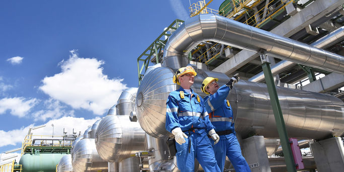 group of industrial workers in a refinery - oil processing equipment and machinery