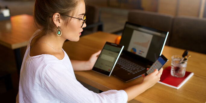 Mixed race woman in glasses working with multiple electronic internet devices